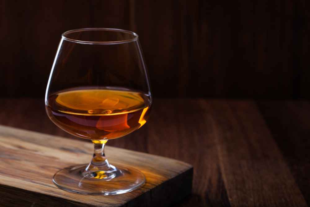 Glass of Cognac Liquor on Wood Plank with Dark Background
